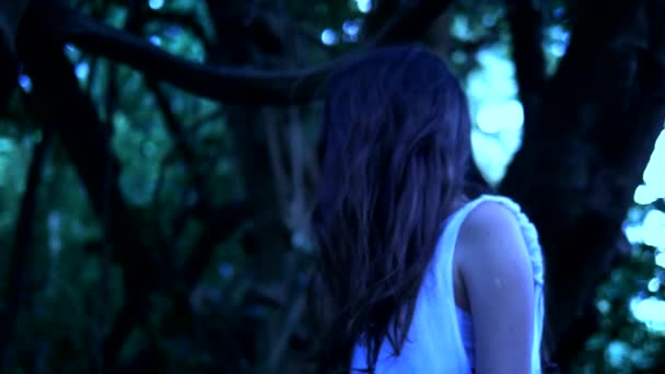 長い黒い顔の髪を持つハロウィーンの幽霊の女の子は、厚い怖い森の中に立っています。クローズ アップ — ストック動画