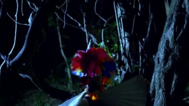 Cadılar Bayramı, geceleri korkunç bir karanlık ormanda boynunda bir yay ile kötü palyaço. yıldırım yanıp söner