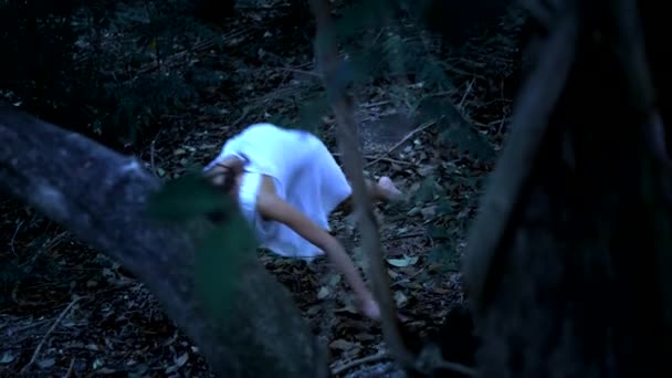 Halloween. a szellem egy lány hosszú fekete haja kúszik a sűrű ijesztő erdőben. Támadás — Stock videók