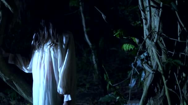Halloween. Geistermädchen mit langen schwarzen Gesichtshaaren steht in einem dicken, beängstigenden Wald aus Blitzen. — Stockvideo
