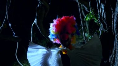 Cadılar Bayramı, geceleri korkunç bir karanlık ormanda boynunda bir yay ile kötü palyaço. yıldırım yanıp söner