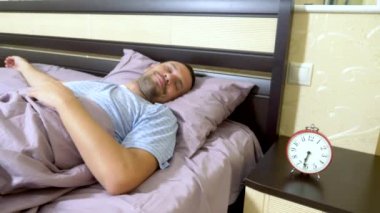 mavi pijama adam sabah uyanır ve onun uyanma sevinir, alarm kapatır