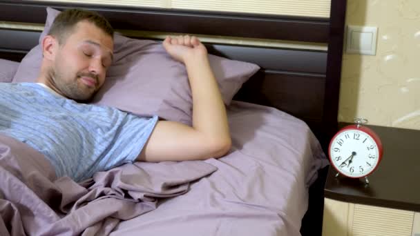Pria dengan piyama biru bangun di pagi hari dan bersukacita saat dia bangun, mematikan alarm — Stok Video