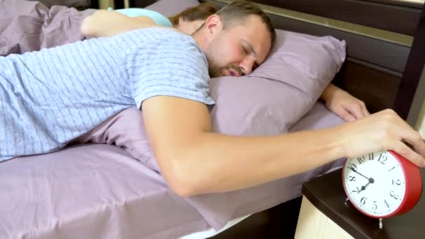 Casal sonolento na cama pela manhã não pode acordar e desliga o alarme — Vídeo de Stock
