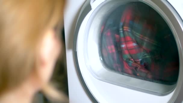 La buanderie est séchée dans un sèche-linge. Gros plan. femme regardant le processus de séchage des vêtements dans le sèche-linge — Video