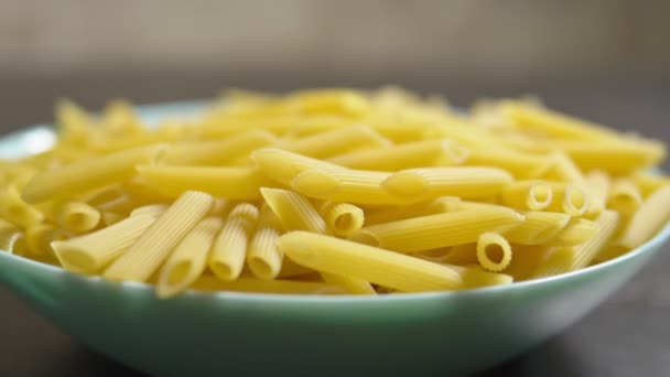 Raw pasta. Penne Rigate, close-up. on a blue plate — Stock Video