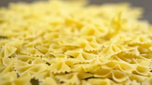 Farfalle zaostřená padá na dřevěný stůl, syrové těstoviny — Stock video