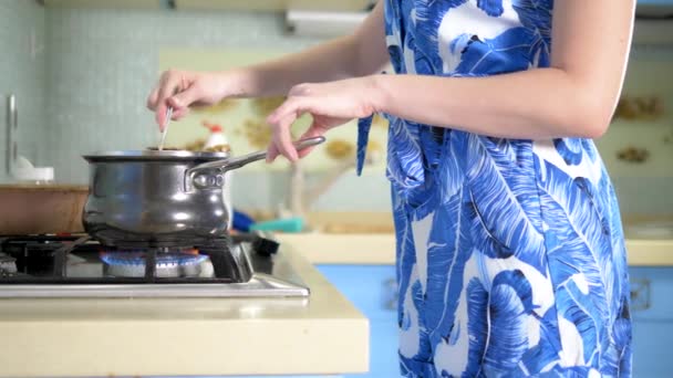 Mujer cocinando en casa en la estufa de gas. primer plano de las caderas — Vídeos de Stock