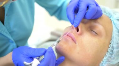Kozmetoloji kavramı. Burun kontur düzeltmesi. Doktor kozmetolojist, hastaların kadının burnuna bir dolgu maddesi enjekte ediyor. Close