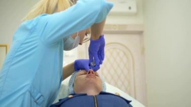 Kozmetoloji kavramı. Burun kontur düzeltmesi. Doktor kozmetolojist, hastaların kadının burnuna bir dolgu maddesi enjekte ediyor. Close