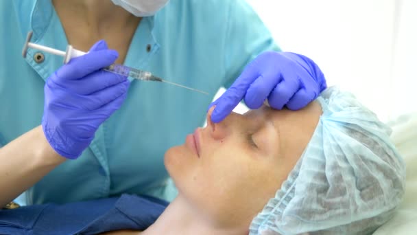 美容学の概念。鼻の輪郭補正。医師の美容師は、患者の女性の鼻に充填剤を注入します。クローズ アップ — ストック動画