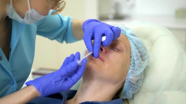 Kozmetoloji kavramı. Burun kontur düzeltmesi. Doktor kozmetolojist, hastaların kadının burnuna bir dolgu maddesi enjekte ediyor. Close — Stok video