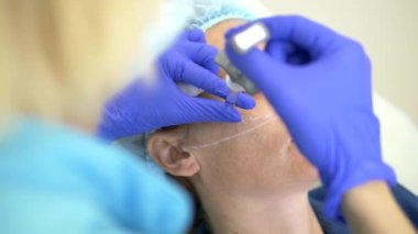 Kontur plastik yüz kavramı. Bir plastik cerrah bir kadının yüzüne dolgu enjeksiyonu enjekte eder. Close.