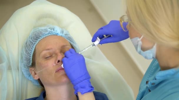 El concepto de contorno de cara de plástico. Un cirujano plástico inyecta una inyección de relleno en la cara de una mujer. primer plano . — Vídeos de Stock