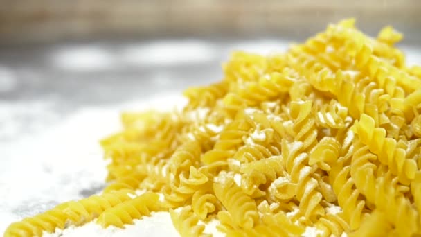 Rauwe pasta Fusilli, close-up liggen in witte bloem op een houten tafel. — Stockvideo