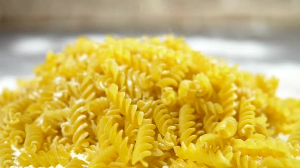 Rå pasta Fusilli, närbild ligger i vitt mjöl på ett träbord. — Stockvideo