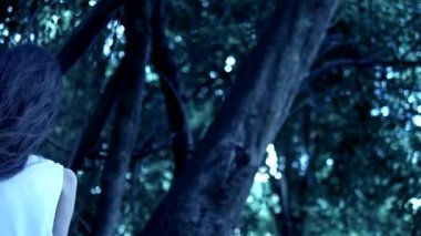 Uzun siyah yüz saçlı bir Cadılar Bayramı hayalet kız kalın bir korkunç ormanda duruyor. Close