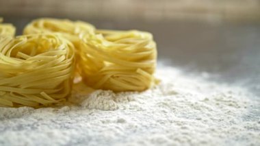 Fettuccine, çiğ makarna, closeup ahşap bir masa üzerinde beyaz un yalan