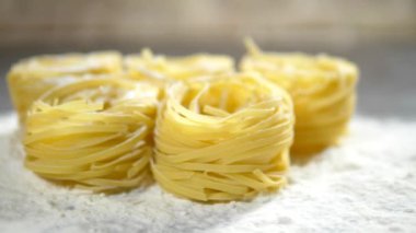 Fettuccine, çiğ makarna, closeup ahşap bir masa üzerinde beyaz un yalan