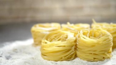 Fettuccine, çiğ makarna, closeup ahşap bir masa üzerinde beyaz un yalan
