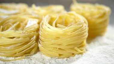 Fettuccine, çiğ makarna, closeup ahşap bir masa üzerinde beyaz un yalan