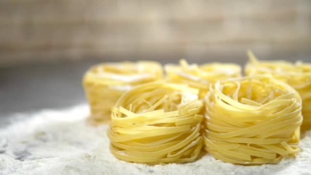 Fettuccine, rå pasta, närbild ligger i vitt mjöl på ett träbord — Stockvideo