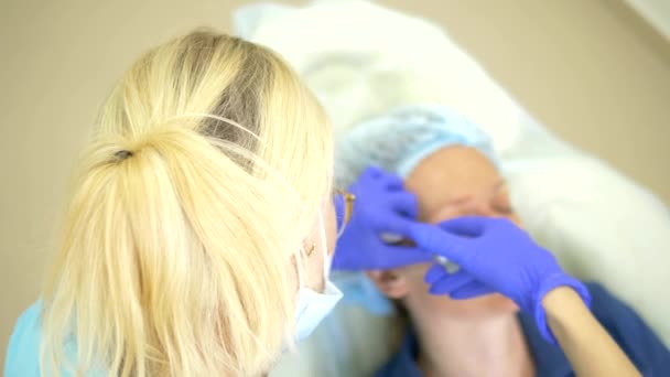 Het concept van Contour plastic gezicht. Een kunststof chirurgen hand zet een filler injectie in het gezicht van een vrouw. Close-up — Stockvideo