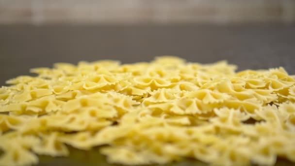 Farfalle close-up vallen op een houten tafel, rauwe pasta — Stockvideo