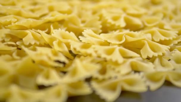 Raw pasta. Farfalle closeup on wooden table — Stock Video