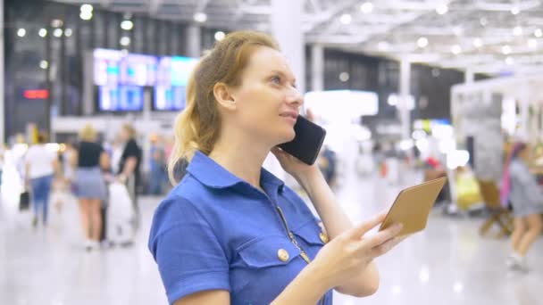 Nainen lentokentällä odotushuoneessa. tyttö istuu käyttää älypuhelinta ja omistaa passin — kuvapankkivideo