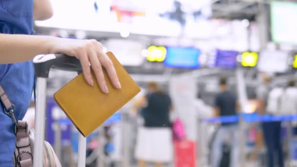 Concepto de turismo y viajes. Primer plano. Las manos femeninas sostienen la manija de la maleta mientras están de pie en la fila en el aeropuerto — Vídeo de stock