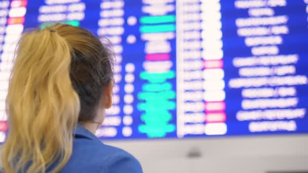 Concept of air travel . woman stands back and looks schedule on scoreboard airport — Stock Video