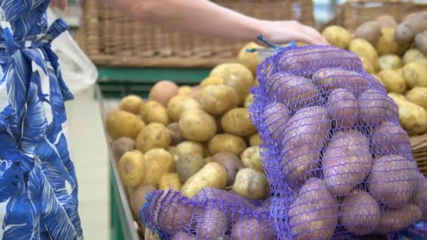 Konzept der sozialen Marktwirtschaft, billige Produkte. Frau pflückt Kartoffeln im Gitter auf der Theke im Laden — Stockvideo