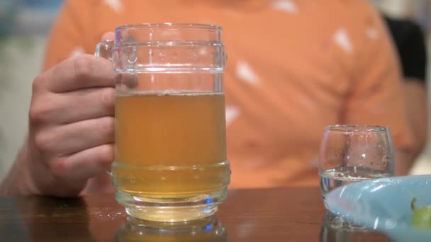 Concepto de alcoholismo, primer plano, un hombre sostiene un vaso de cerveza y un vaso de vodka — Vídeo de stock