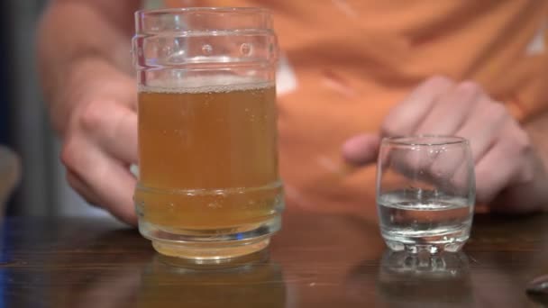 Ιδέα του αλκοολισμού, κοντινό, ένας άντρας κρατά ένα ποτήρι μπύρας και ένα ποτήρι βότκα — Αρχείο Βίντεο