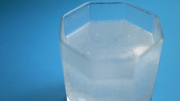 Primo piano. pillola sciogliere in acqua con bolle su sfondo blu. copia spazio — Video Stock