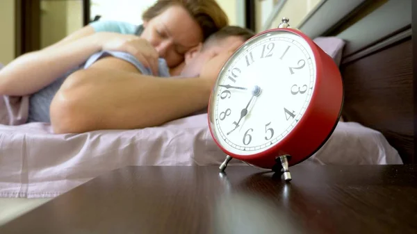 Schläfriges Paar kann morgens nicht aufwachen und schaltet den Wecker aus — Stockfoto