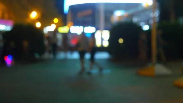 ผู้คนเดินผ่านเมืองกลางคืน พื้นหลังที่เบลอสดใสแบบนามธรรมกับบ็อกเฮที่สดใส คอนเซปต์ไนท์ไลฟ์ในเมืองสมัยใหม่ — ภาพถ่ายสต็อก
