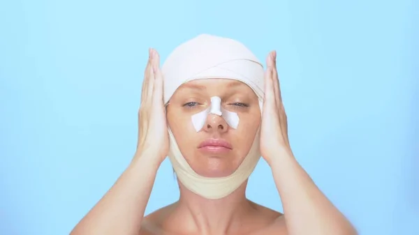 Koncepcja chirurgii plastycznej. Plastyka powiek, Blepharoplastyka, lifting twarzy. Portret kobiety z bandaż na głowie, nos i oczy. na niebieskim tle — Zdjęcie stockowe