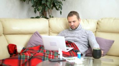 bir süveter kanepede oturan soğuk bir adam ve bir ekose video bağlantısı üzerinden bir dizüstü bilgisayar üzerinde Doktor çağırma.