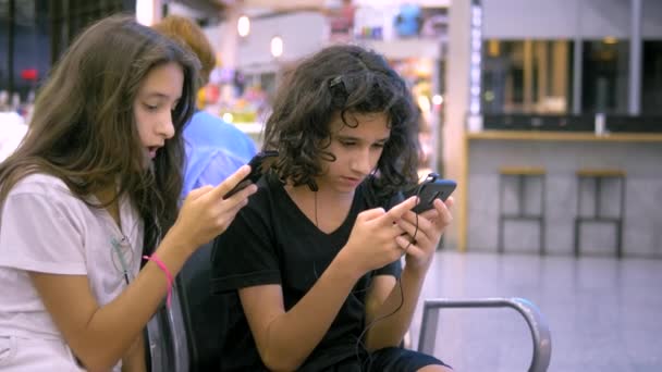 Havaalanında bekleyen çocuklar bir akıllı telefon kullanır. seyahat konsepti — Stok video