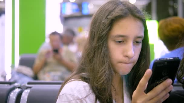 Menina adolescente na área de espera do aeroporto usando smartphone. conceito de viagem — Vídeo de Stock