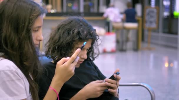 Los niños en la sala de espera del aeropuerto utilizan un teléfono inteligente. concepto de viaje — Vídeos de Stock