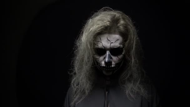 Koncept, krásný make-up na Halloween. Portrét mladé sexy dívky s lebkou. na černém pozadí, tvář ve tmě. Close-up — Stock video