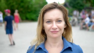 Güzel genç kadın sarışın, kamera bakarak, yakın çekim. arka planda insanların kalabalığı, bulanıklaşıyor