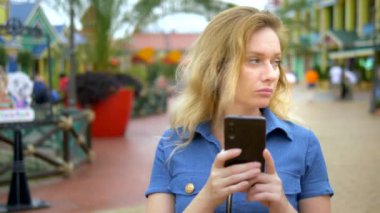 Bir kadın bir smartphone cep telefonu ile eski ahşap evler arasında duran, bir harita uygulaması kullanır. Bergen, Norveç