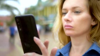 Genç ve çekici bir kadının yüzü şehir merkezindeki telefonu kullanır. yaz güneşli bir gün. Close .
