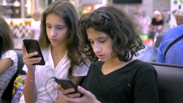 Los niños en la sala de espera del aeropuerto utilizan un teléfono inteligente. concepto de viaje — Vídeo de stock