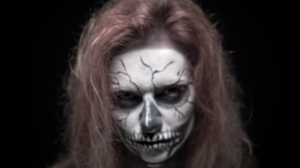 Concepto, hermoso maquillaje para Halloween. Retrato de una chica sexy joven con maquillaje de cráneo. sobre un fondo negro, cara en la oscuridad. primer plano — Vídeos de Stock