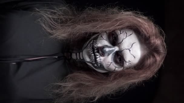 Koncept, krásný make-up na Halloween. Portrét mladé sexy dívky s lebkou. na černém pozadí, tvář ve tmě. zblízka, vodorovně. — Stock video